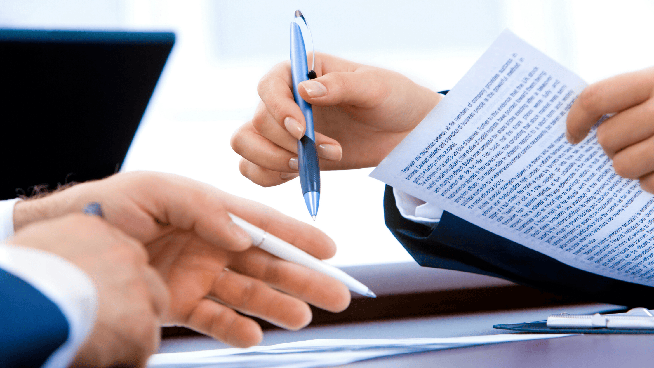 Two professionals in business attire hold pens and examine a printed contract—potentially a bespoke Canadian life insurance policy—at a desk, collaborating on advanced wealth management solutions from Safe Pacific Financial. The scene suggests an in-depth discussion of the Infinite Banking Strategy and tailored financial advice for affluent families, with a laptop partially visible in the background.