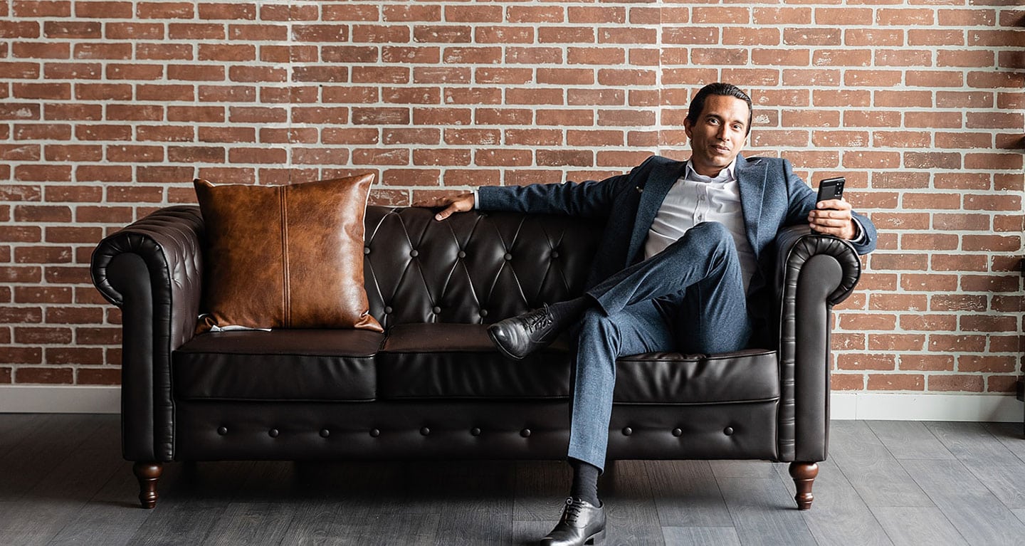 laurent munier of safe pacific financial sitting on a couch looking at a mobile phone