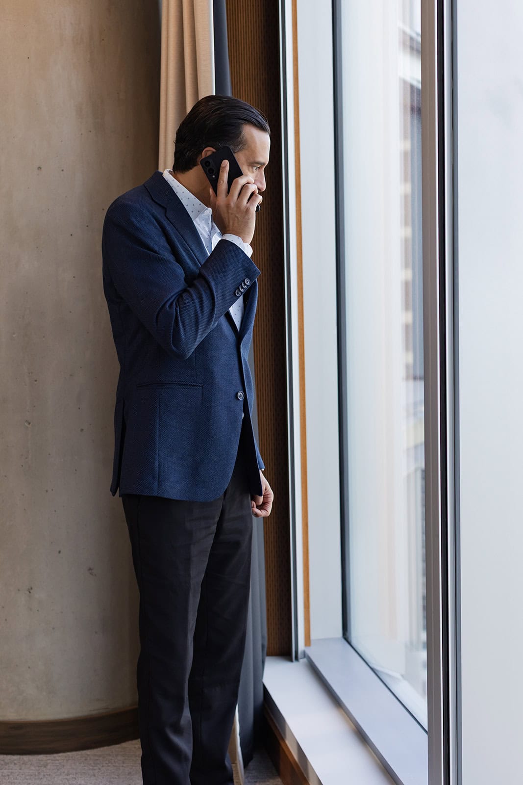 A Safe Pacific Financial advisor in a blue blazer stands by a bright window, consulting on infinite banking and bespoke life insurance.