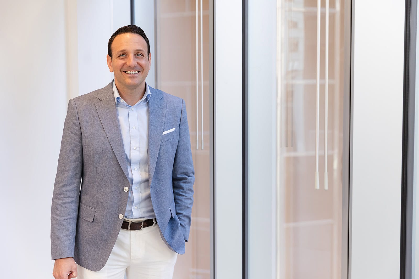 A smiling man in a blue blazer exudes confidence, reflecting Safe Pacific's wealth management and infinite banking advice for affluent Canadians.