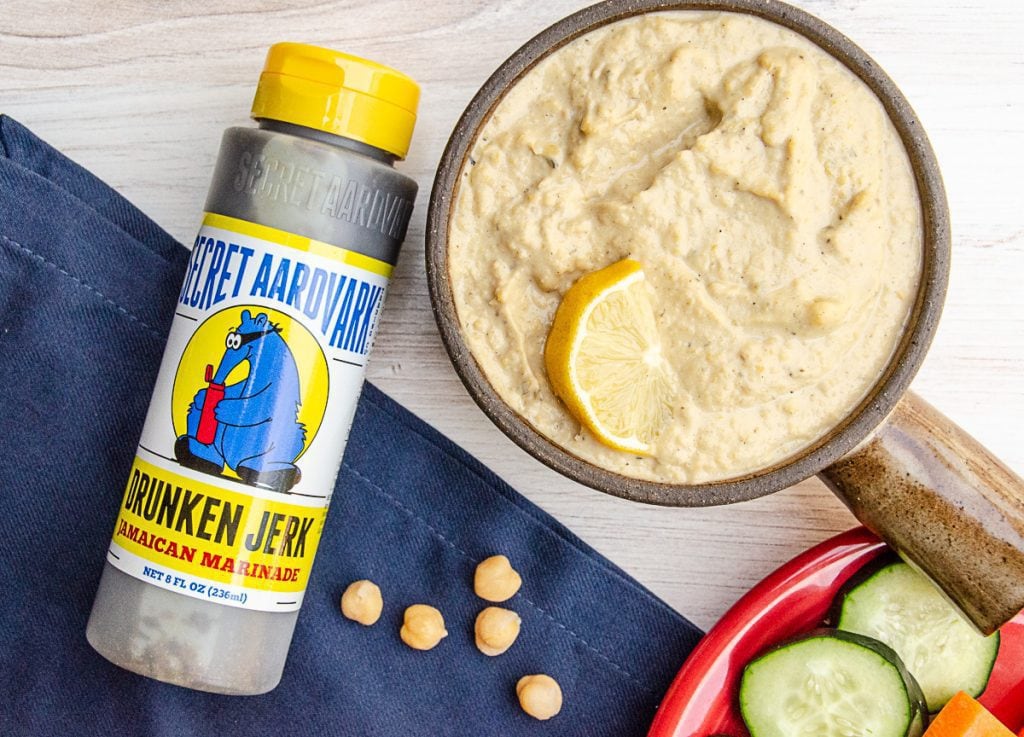 Secret Aardvark Drunken Jerk Jamaican Marinade bottle next to a bowl of hummus
