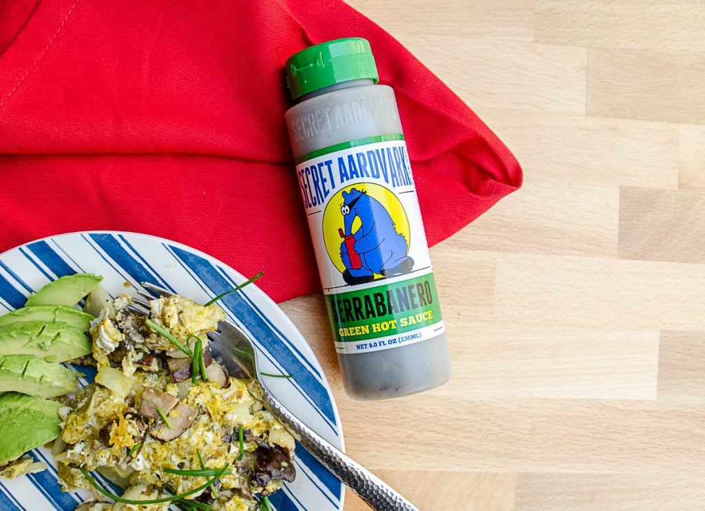 Serrabanero Green hot sauce next to eggs and avocados