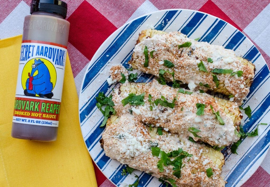 Reaper bottle next to Scorchin' Reaper Elote on a plate.