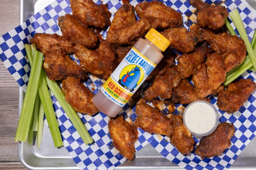 Tray of chicken wings, dipping sauce, celery stick and bottle of Secret Aardvark Red Scorpion Fiery Hot Sauce.
