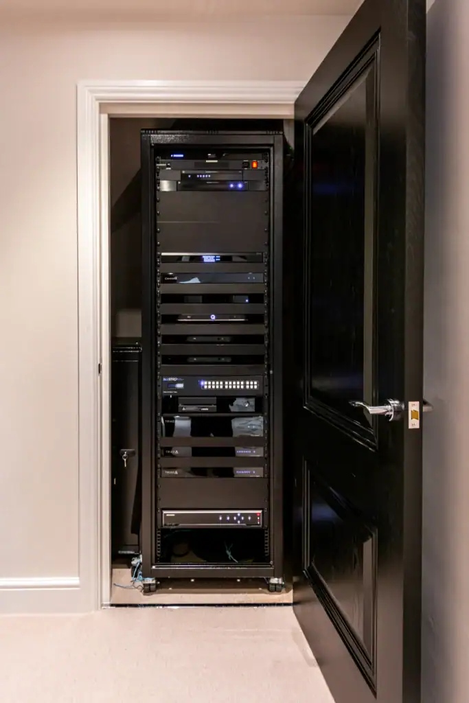 AV equipment rack in a cupboard behind a black door