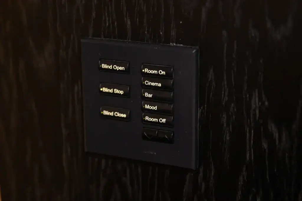 Lighting and blind control keypad with labelled scene buttons on a dark wall