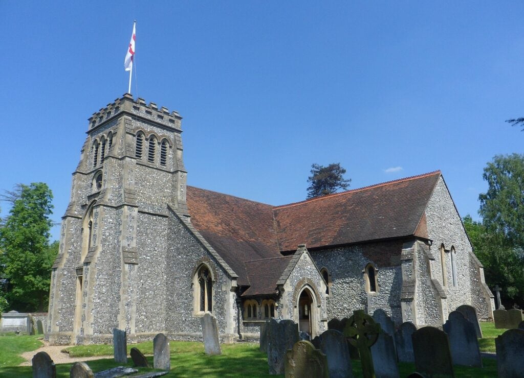 St Lawrence's Church, Effingham, a flint church with a stone tower, seen from the churchyard. Photo: Hassocks5489, CC0