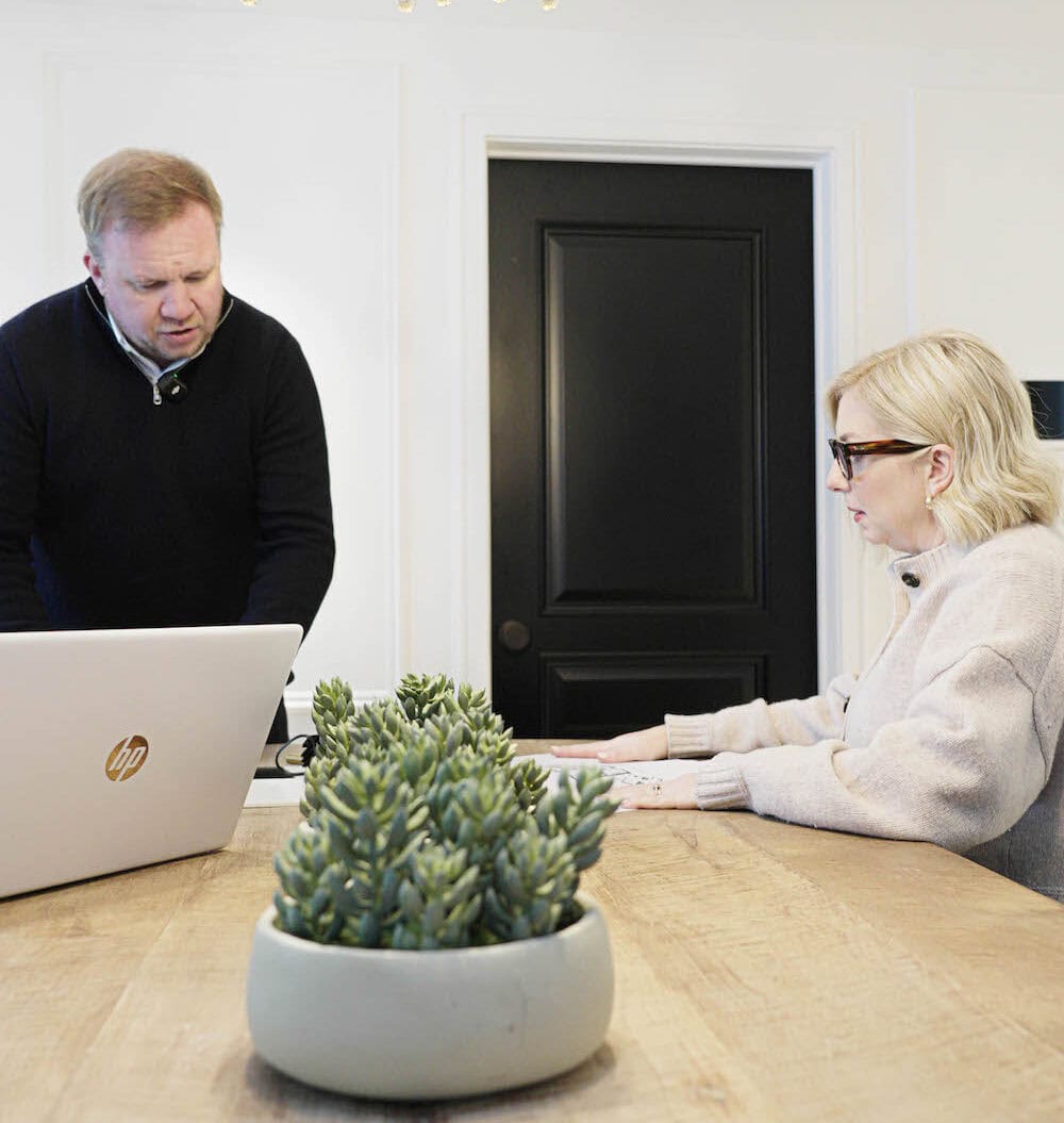 A member of the Art of Integration team talking a client through plans at a wooden table in the showroom