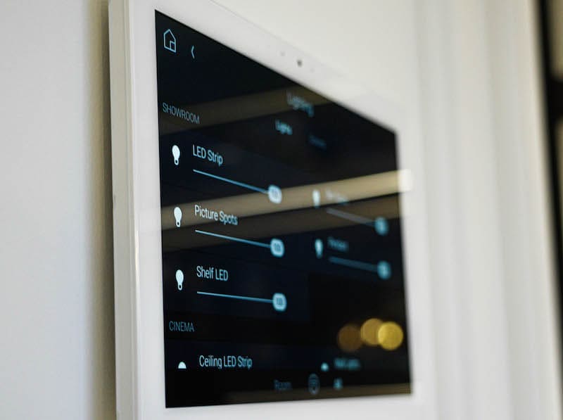 Wall touchscreen in the showroom showing lighting sliders for the LED strip, picture spots, shelf LEDs and the cinema ceiling LED strip