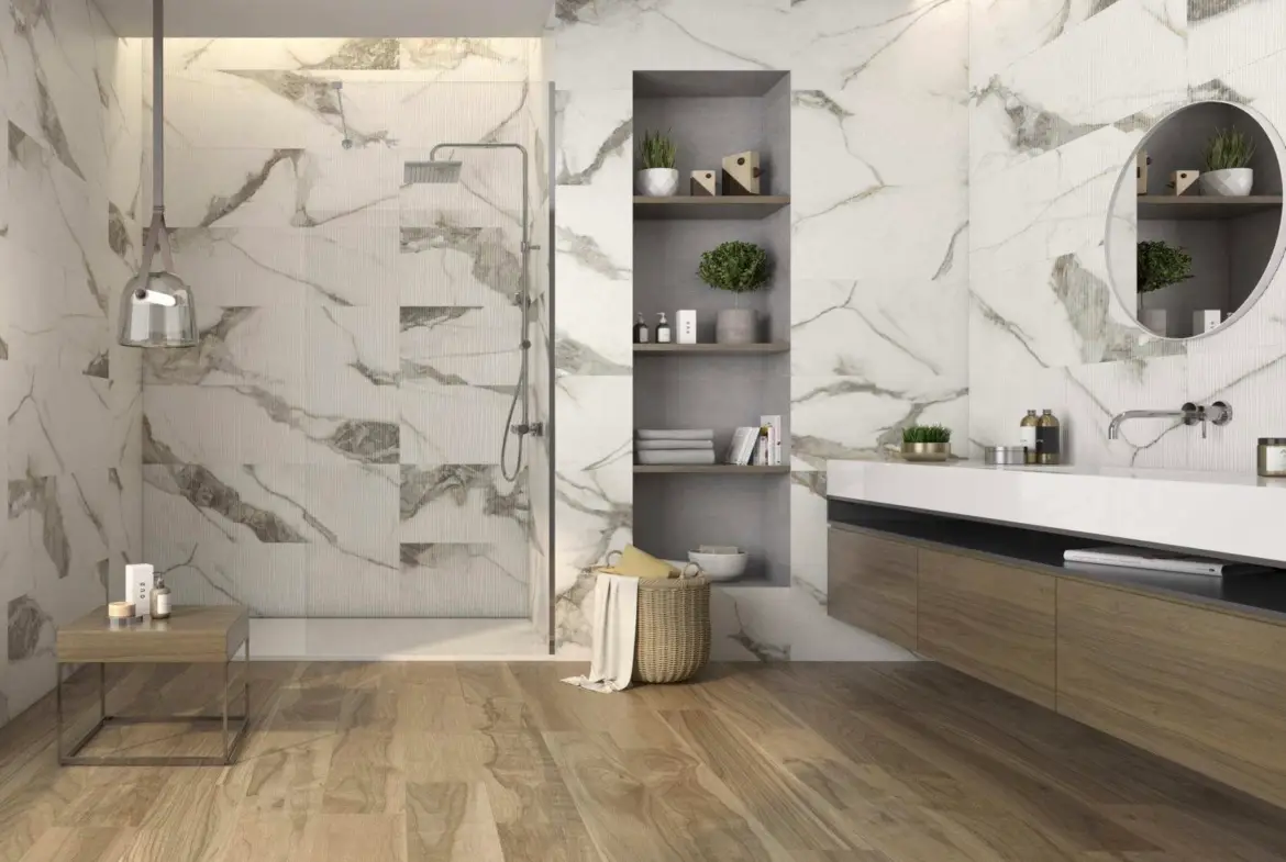 Designová koupelna v apartmánu ve Fuengirole, Španělsko. Prostor nabízí velký walk-in sprchový kout, velkoformátové obklady, závěsnou umyvadlovou skříňku v dekoru dřeva a velké zrcadlo s ambientním podsvícením. Tento design je typický pro vysoký standard nemovitostí na pobřeží Costa del Sol