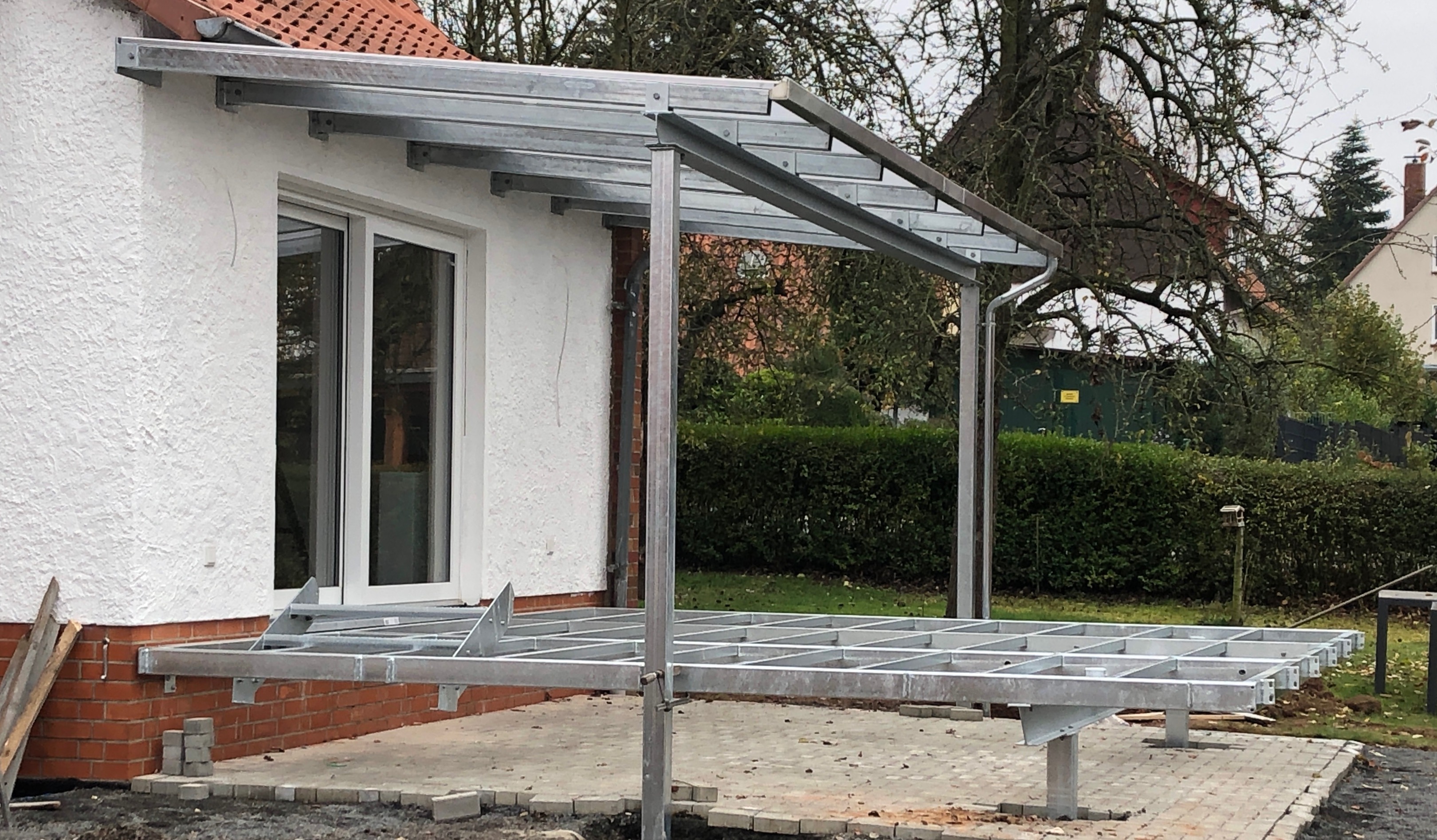 Verzinktes Stahlgerüst für einen Balkon und eine Terrassenüberdachung von Stahl- und Metallbau Drost, im Bau an einem Wohnhaus mit weißer Fassade.