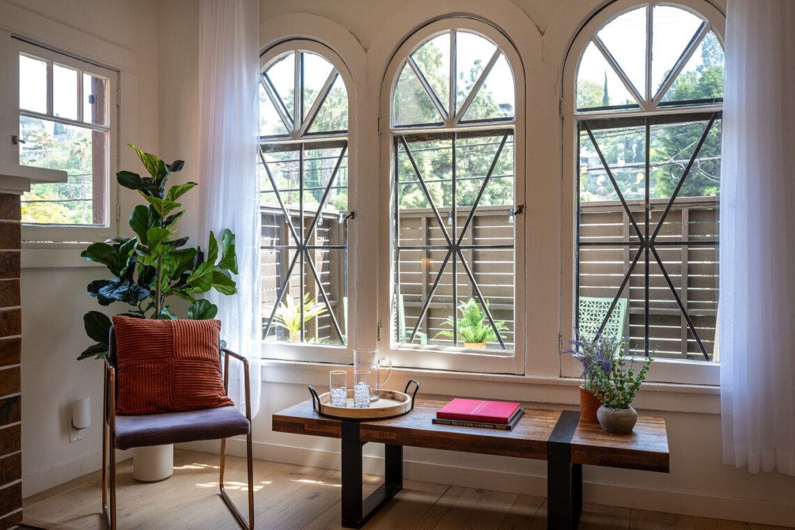 A sunlit corner framed by original arched windows, offering a quiet place to read or unwind. With leafy views and soft light, it’s a peaceful spot to settle into the rhythm of the neighborhood.