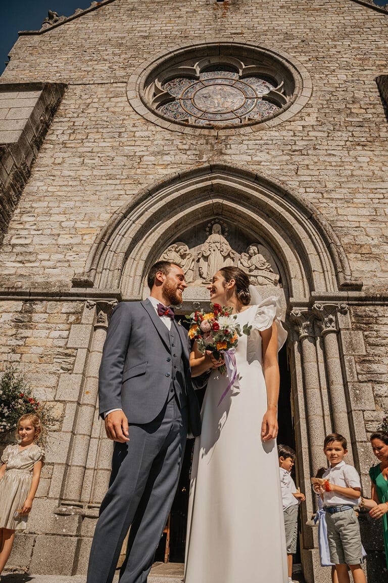 mariés devant l'église après leur cérémonie avec leur photographe de mariage à rennes