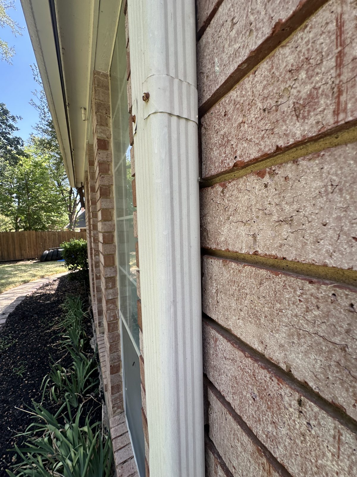 Close-up of brick wall and gutter with no visible roof features or damage.