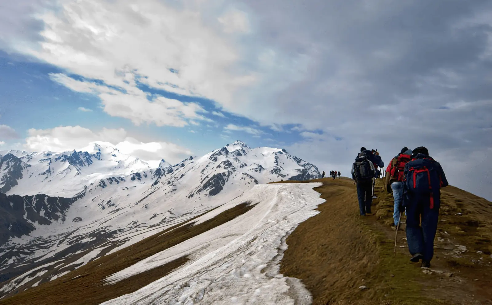 Adventure seekers on the Sar Pass trail surrounded by towering snow-capped peaks.