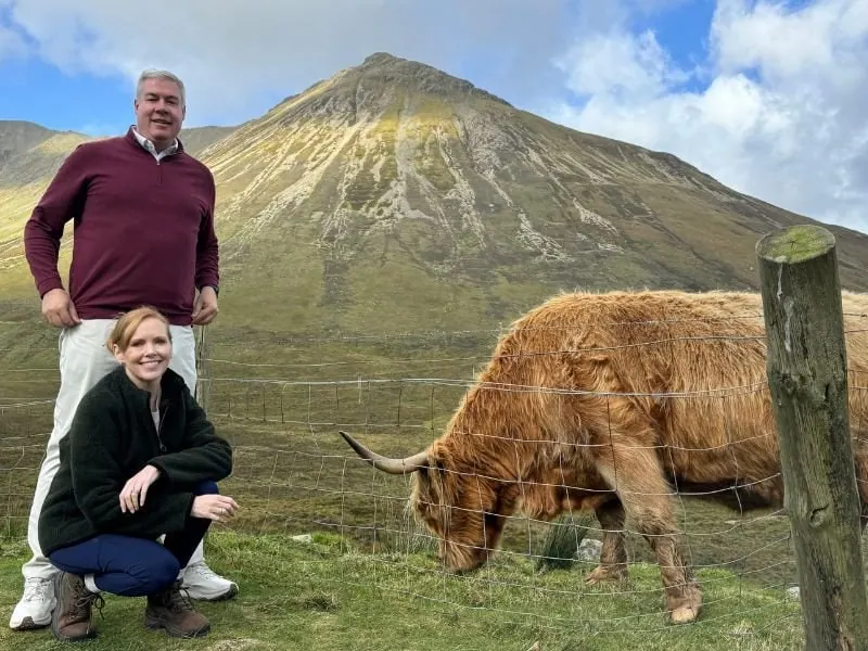 Tourists posing with Highland Cows in front of Glamaig mountain on The isle of skye on our 5 day tour of the island of sky tour at www.tourguidescotland..com