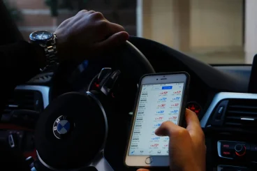 pexels-photo-2068664-2068664 Person using mobile phone for currency trading while driving BMW car.