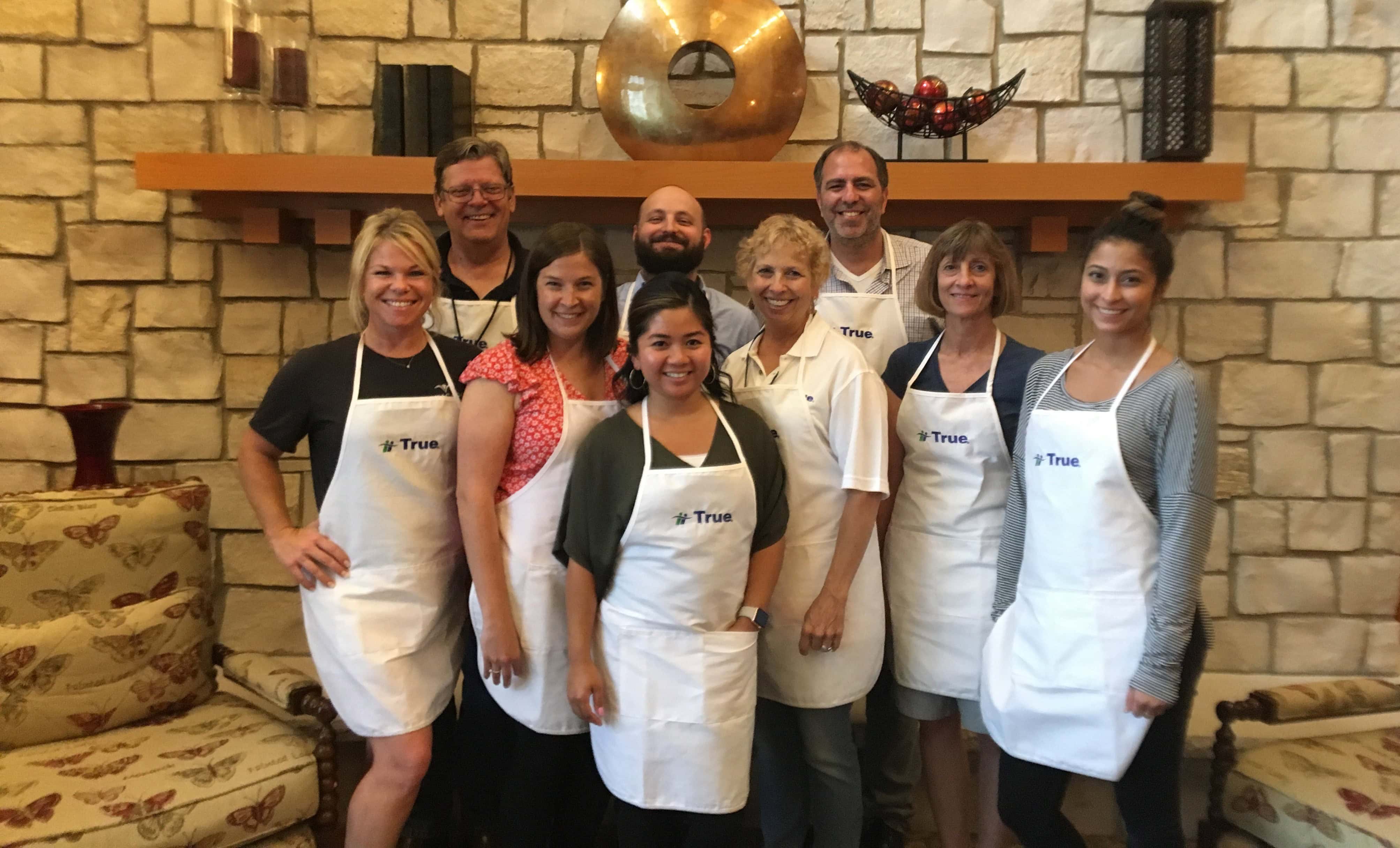 Group of volunteers smiling in white aprons.