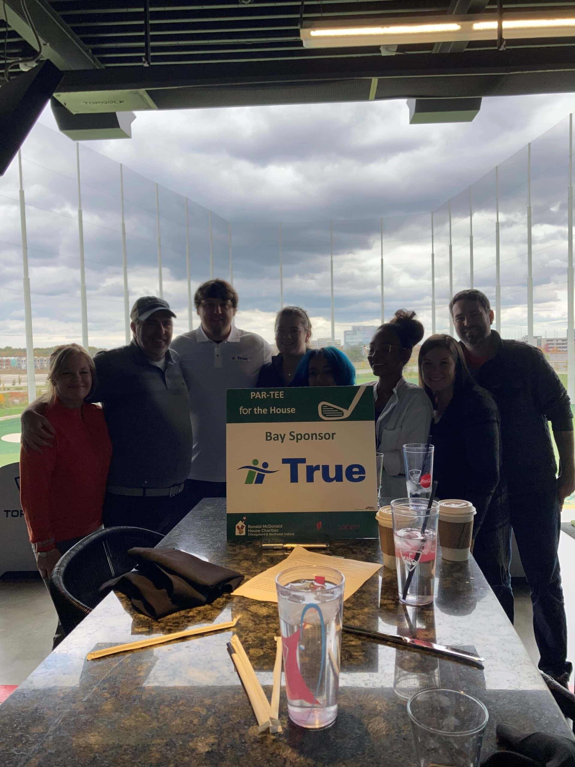 Group of people posing with a sponsorship sign.