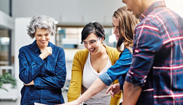 Laptop, diversity and designer team laughing at meme on social media or planning collaboration together at a startup. internet, strategy and small business group of employees streaming joke on news.