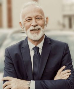 Elderly business man smiling  in front a car