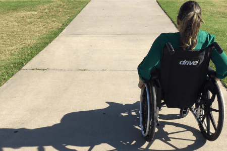 Personne en fauteuil roulant sur un trottoir de béton