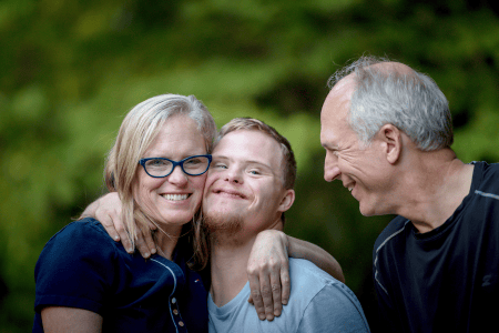 Photo - Jeune homme présentant une déficience intellectuelle entouré de ses parents