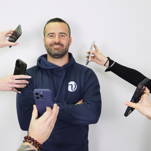 Sans-titre-4 "Homme souriant en sweat à capuche bleu Vircom entouré de plusieurs mains tenant des téléphones"