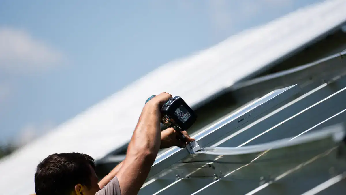 Montator fixând un panou fotovoltaic pe structură