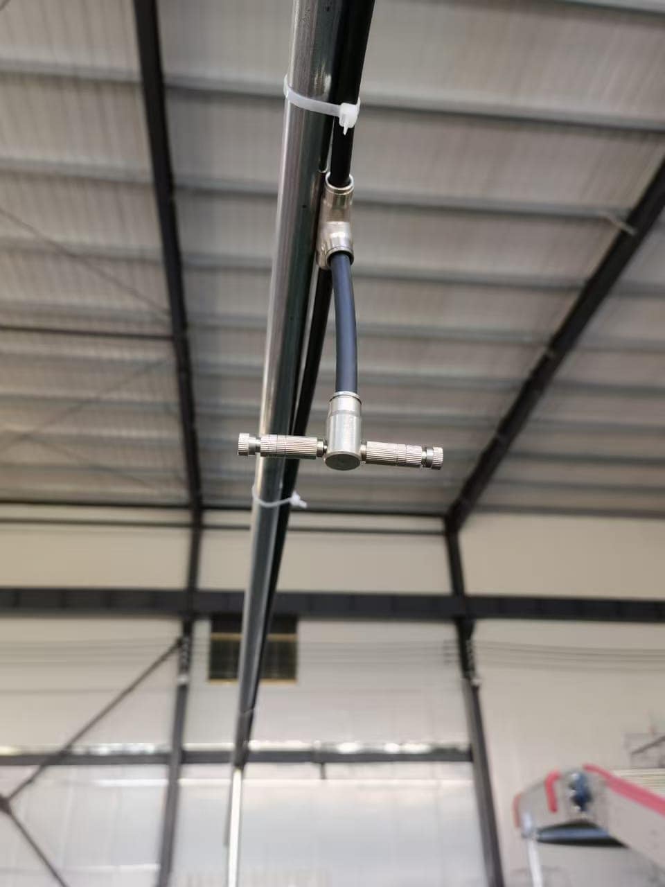 Automated high-pressure misting system with stainless steel nozzles installed in commercial multi-tier poultry house