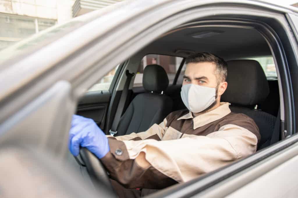 Young man in protective gloves, mask and workwear looking at you in car Manage Your restaurant delivery audience