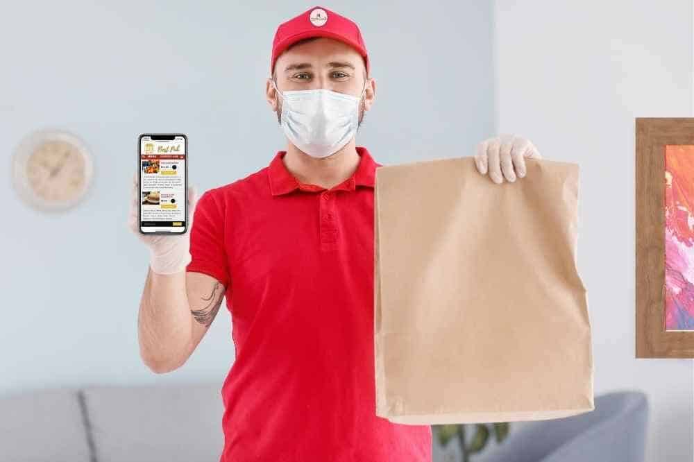 restaurant-online-ordering-curbside-pickup delivery driver wearing facemask holding cell phone with online ordering app open