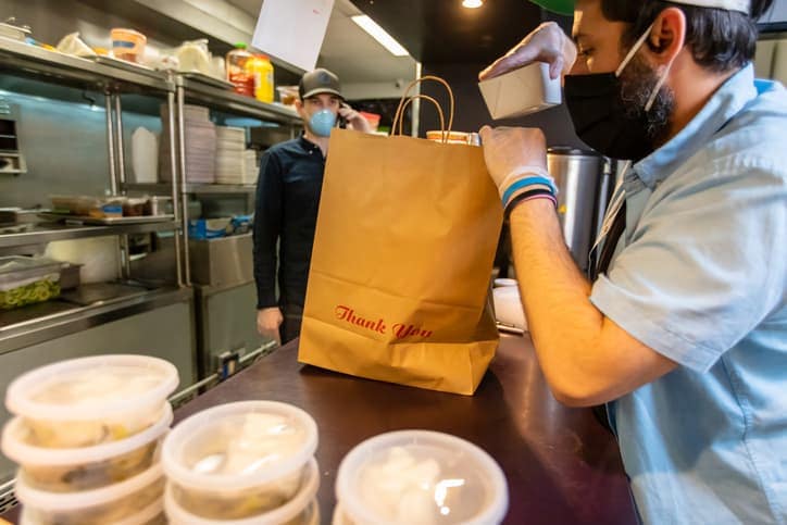 Owners of Local Restaurant Taking Orders on the Phone and Boxing Food for Delivery During Covid-19 Pandemic virtual kitchen restaurant concepts