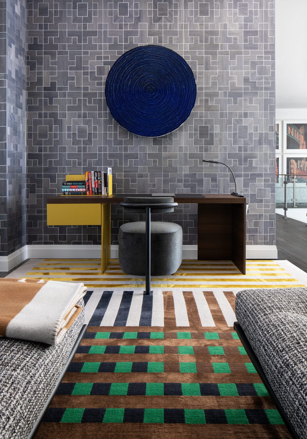 Upstairs lounge with a gray tile feature wall, a cobalt woven wall disc, a mustard desk and a green checked rug