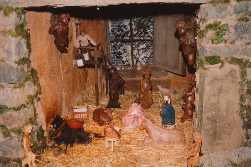 En el portal de belén se ve nevar por la ventana.