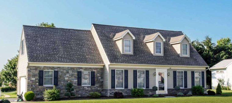 home with stone facade and gray roof with blue sky