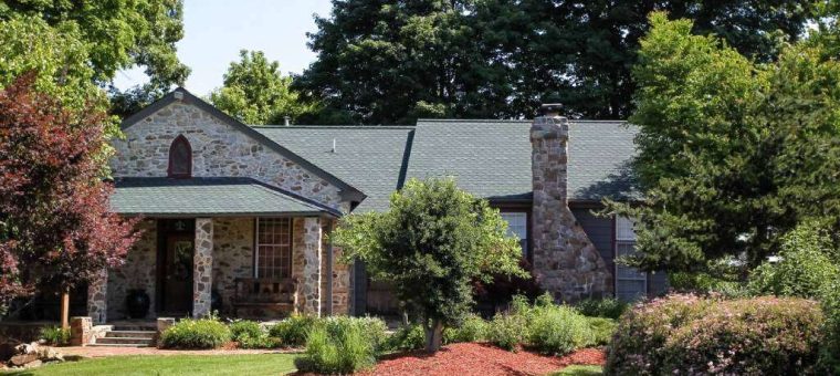 home with stone walls and roof with green shingles