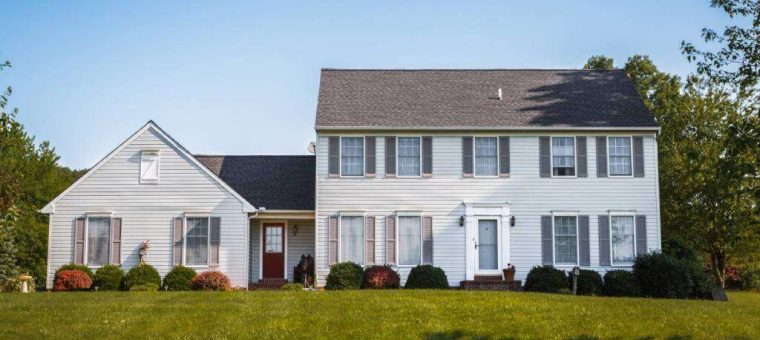 two story beige home with gray roof under blue sky