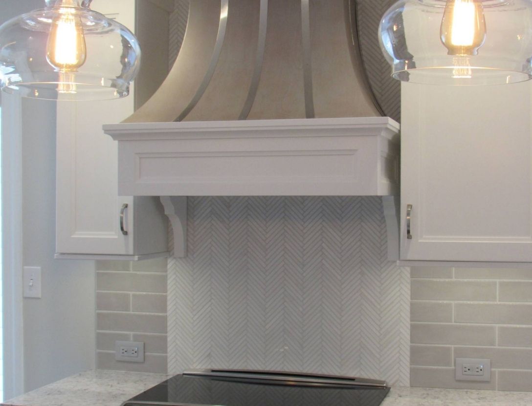 White kitchen backsplash underneath modern oven hood