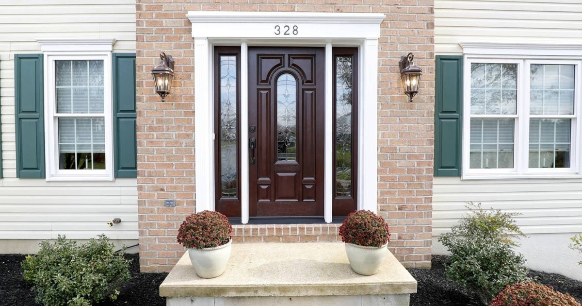 small front porch slab with planters on either side with a brown front door with white trim around the outside
