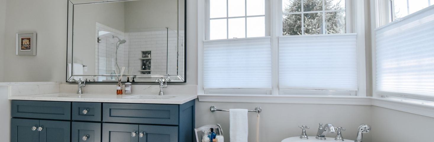 luxury bathroom renovation with blue vanity and large mirror