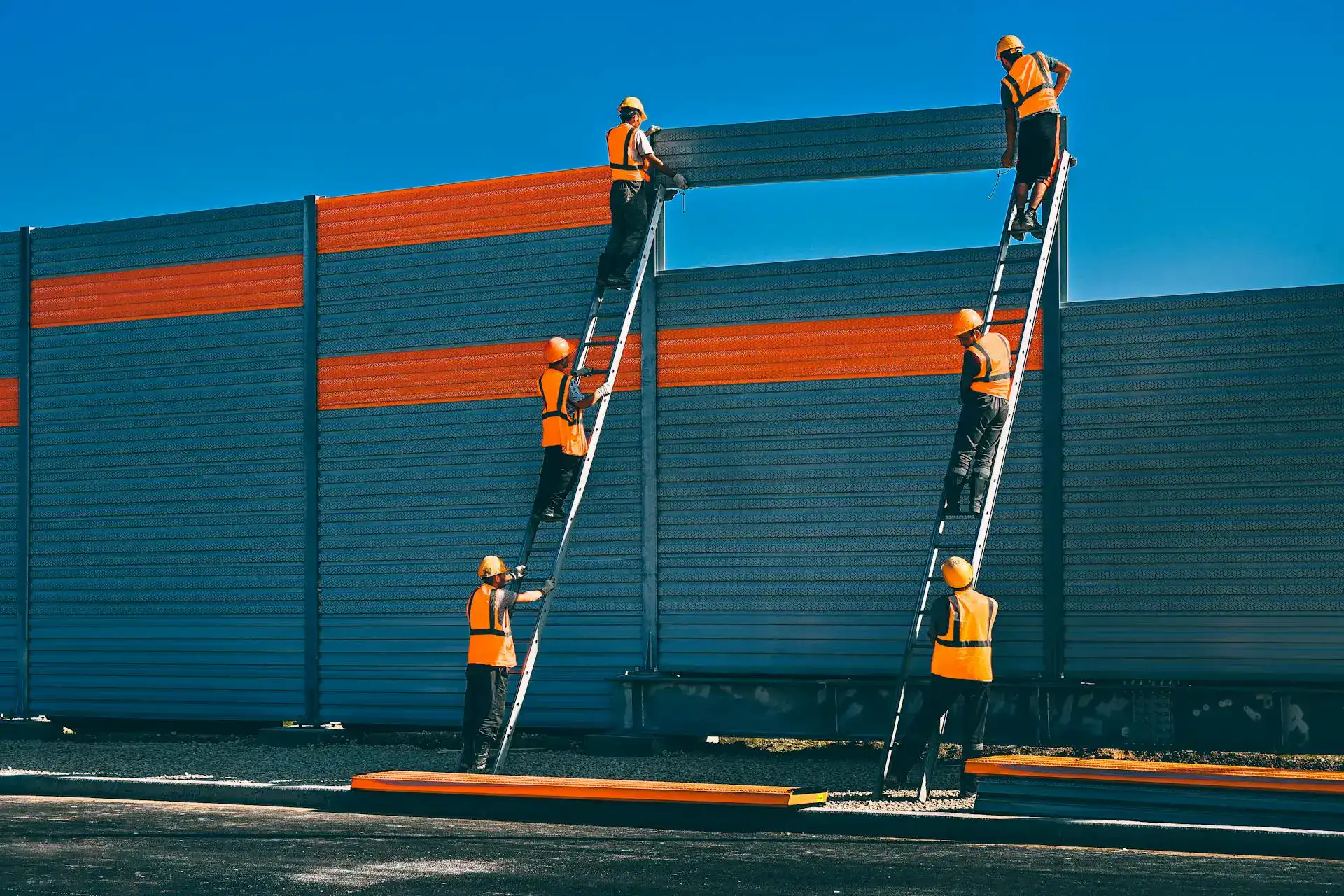 Workers in safety gear install a noise barrier on a highway in Dallas