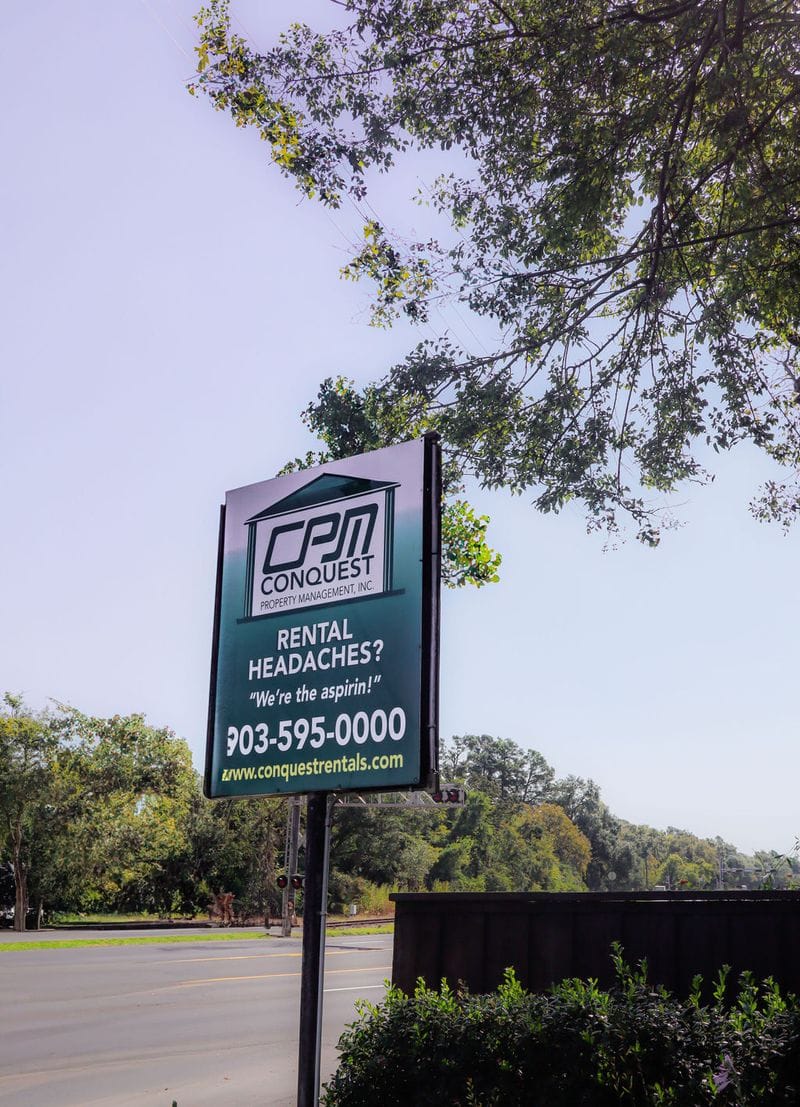 Conquest Property Management road sign — Rental Headaches? We're the aspirin!