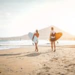 Happy surfers running with surfboards on the beach