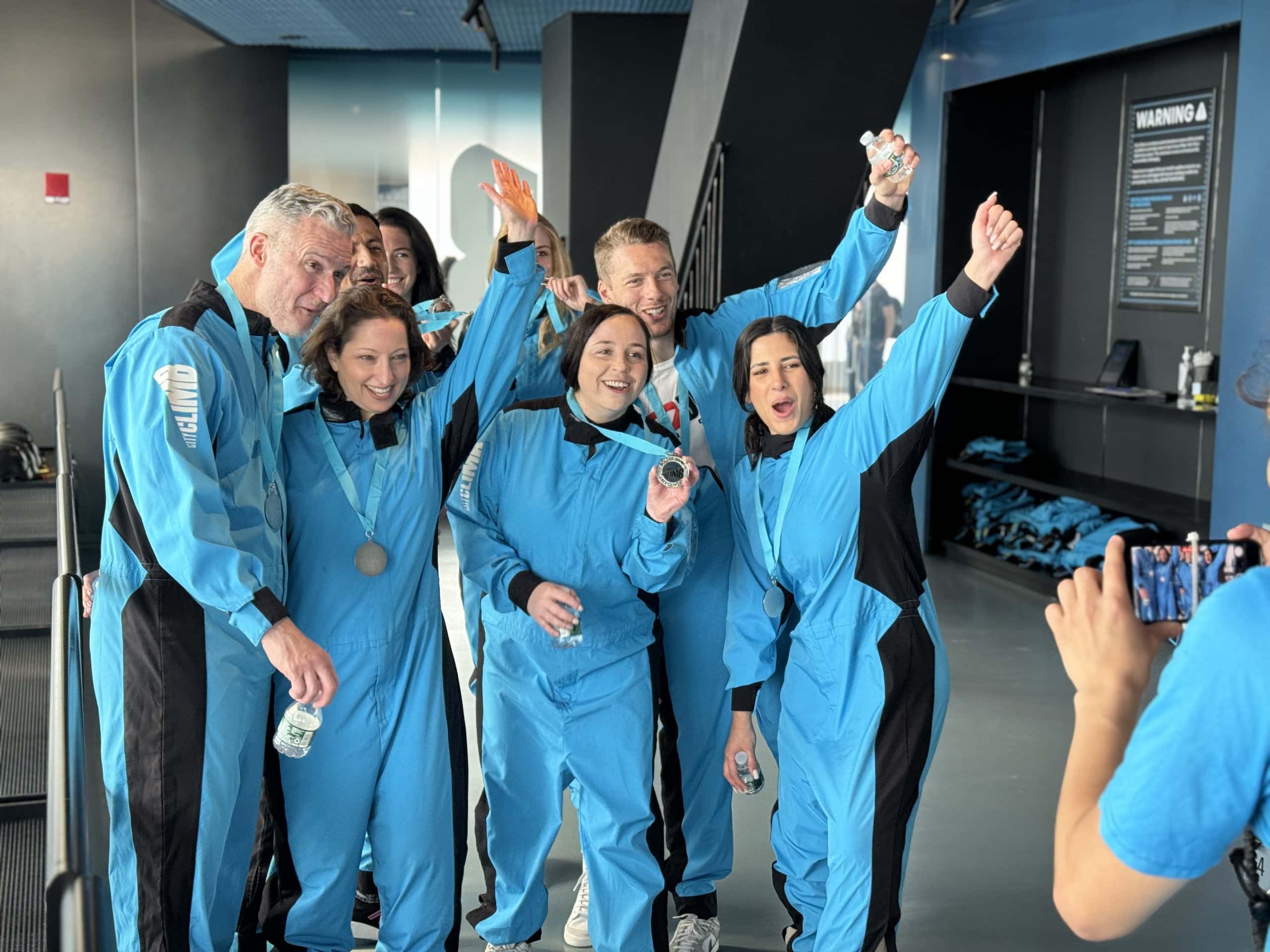 A group of people cheer for a picture after participating in City Climb at The Edge