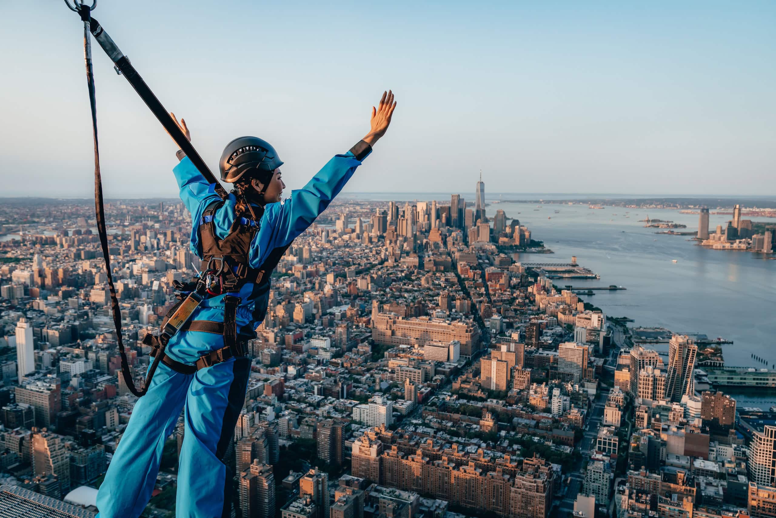 A woman raises her hands in the air in excitement as she leans out during City Climb at The Edge