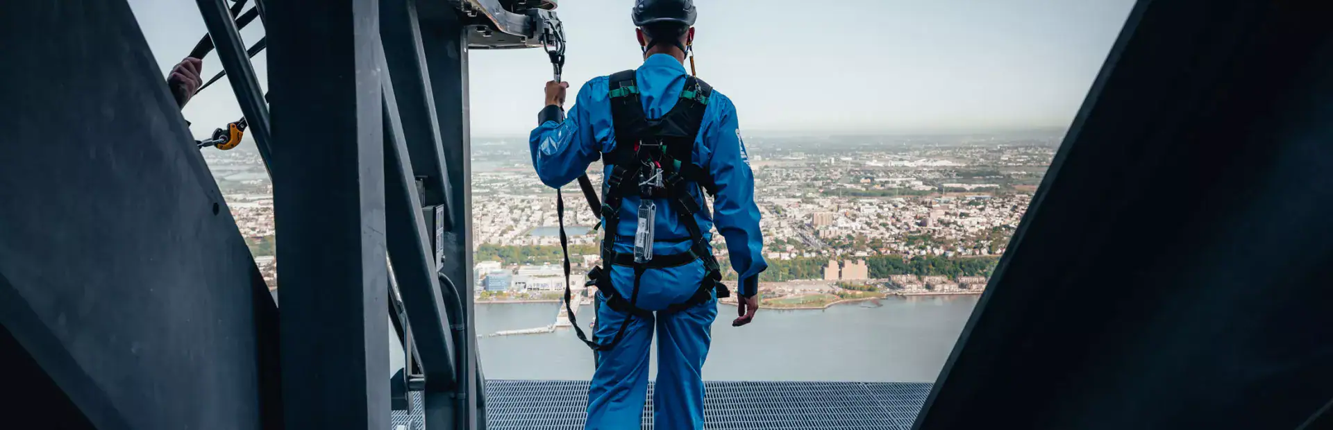 A man in City Climb gear walking out to The Edge City Climb platform overlooking New York City