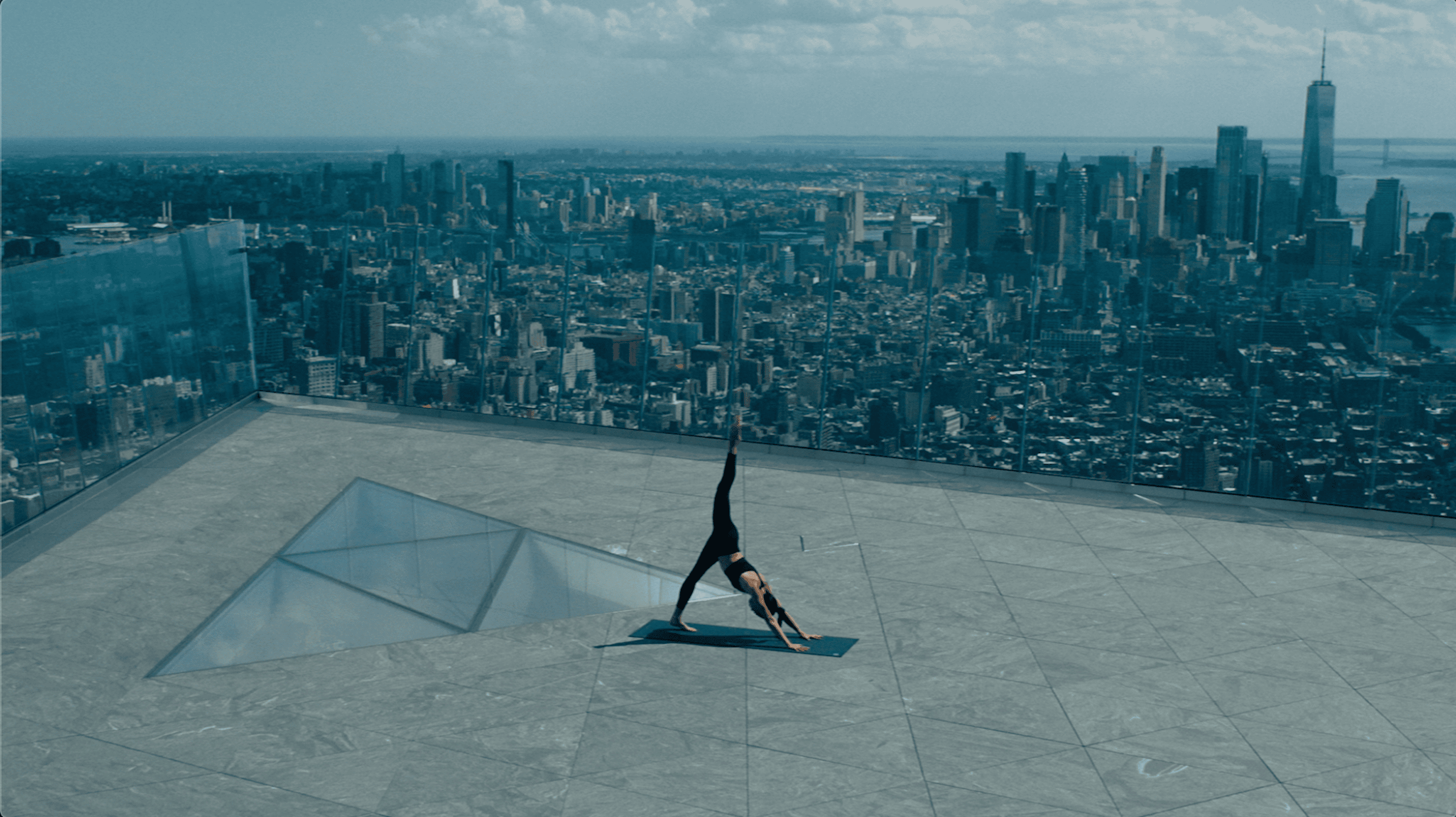 A woman does a yoga pose at The Edge overlooking New York city
