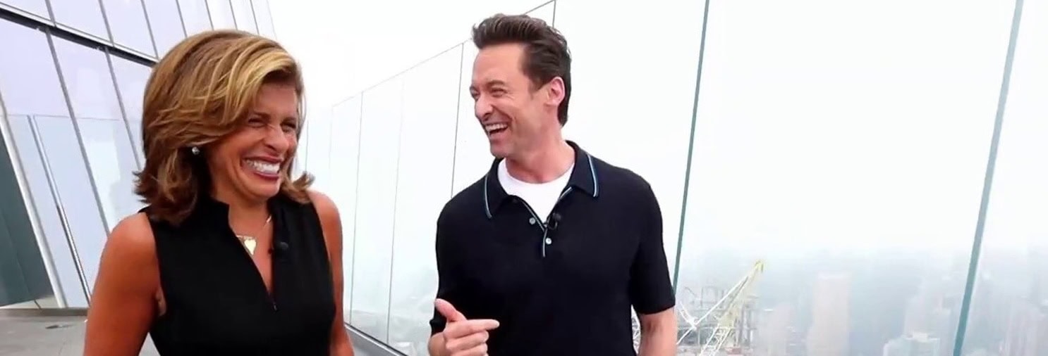 Hugh Jackman is laughing with a reporter outside at The Edge NYC