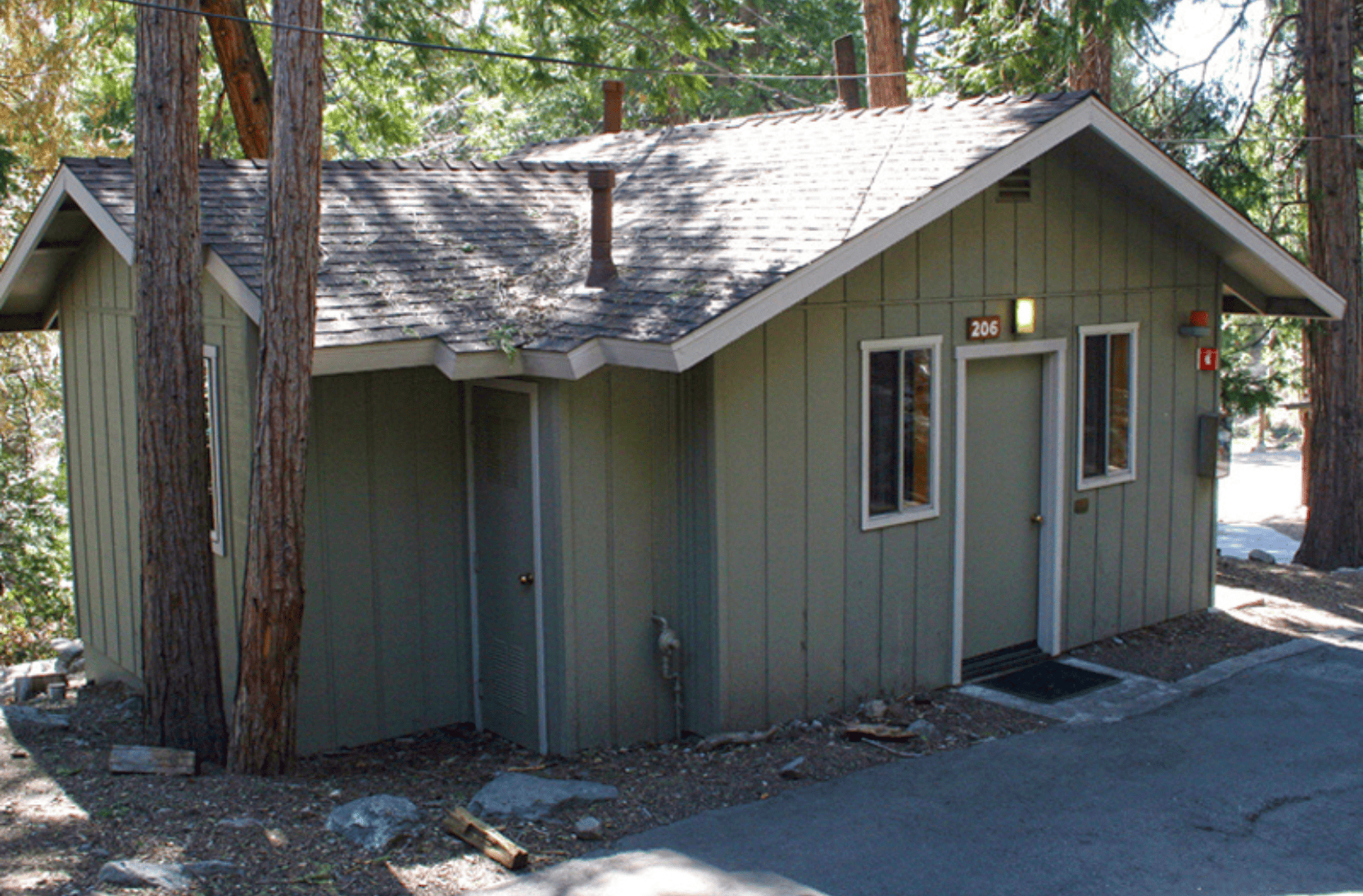 Outside view of a cabin at Forest Home with green extrior in the mountains